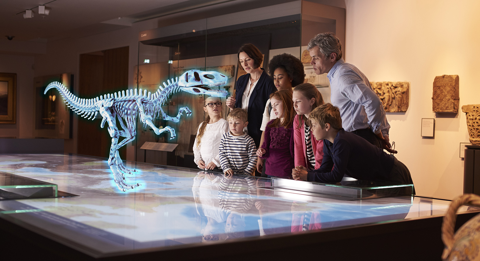 group of people at museum seeing dinosaur hologram on a map