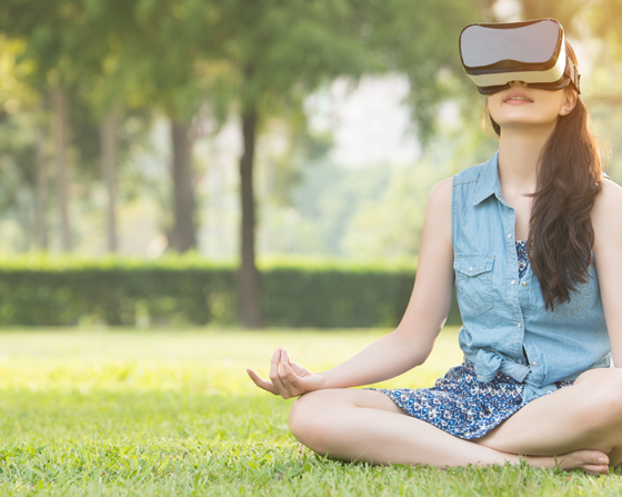 young female meditating with virtual reality headset in park