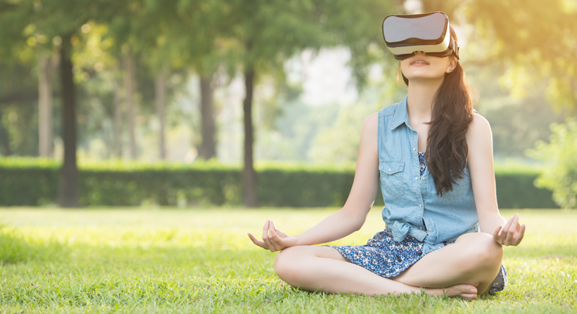 young female meditating with virtual reality headset in park