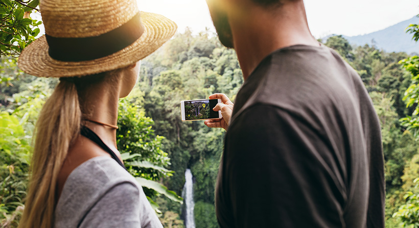 Young couple hiking and checking augmented reality app in their phone