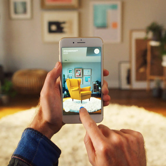 Male customer holding smart phone and decorating his room through IKEA AR App
