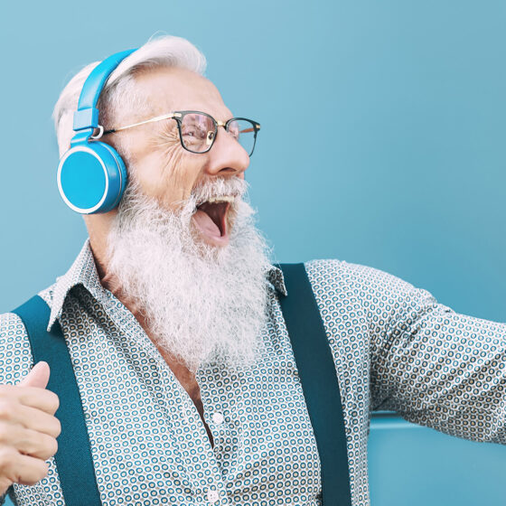 Happy senior male having fun using mobile smartphone playlist apps - technology and elderly lifestyle people concept for digital marketing