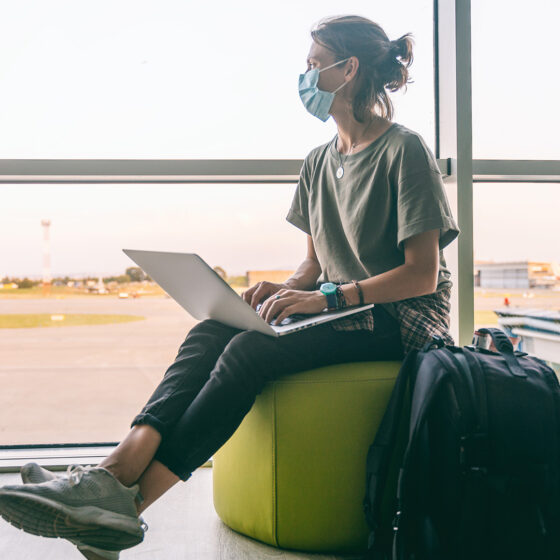 young digital nomad woman wearing a medical mask waiting for her plane at the airport in a post-pandemic world