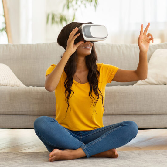 Young black woman in VR headset touching air during virtual reality experience at home during COVID lockdowns