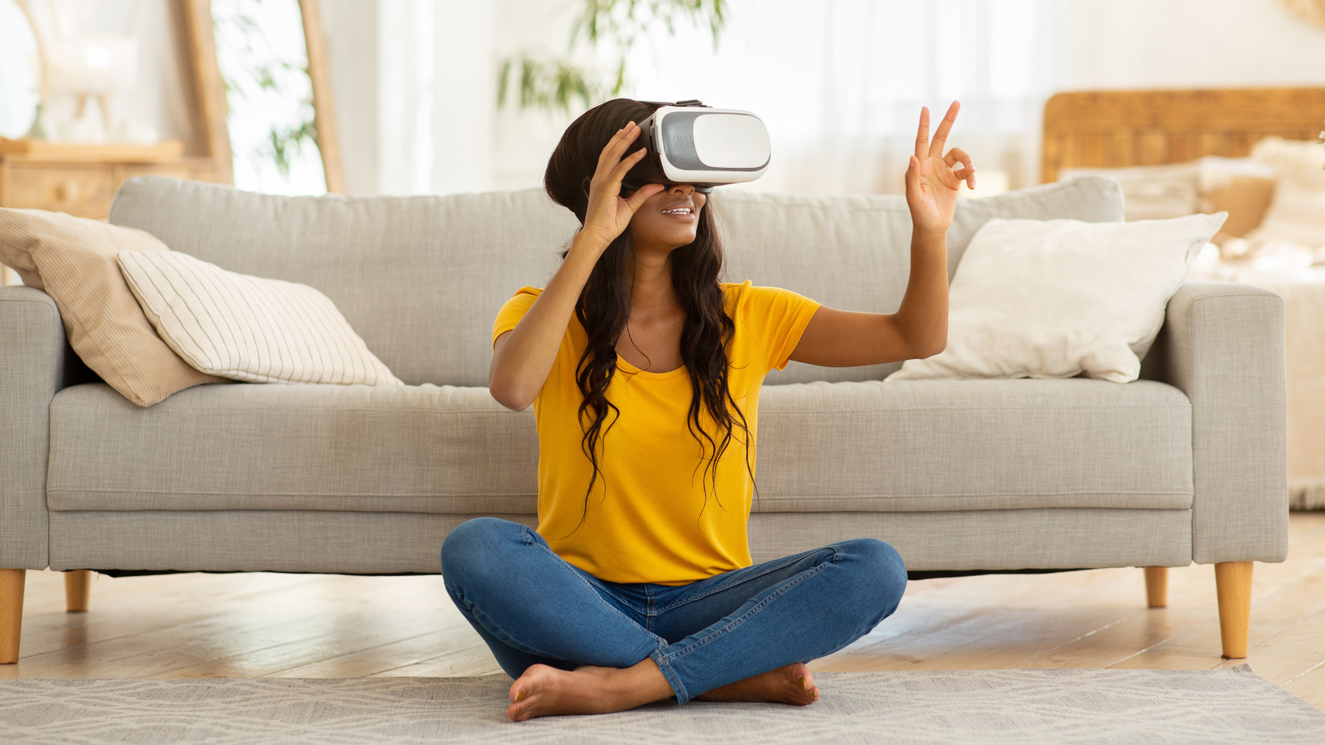 Young black woman in VR headset touching air during virtual reality experience at home during COVID lockdowns