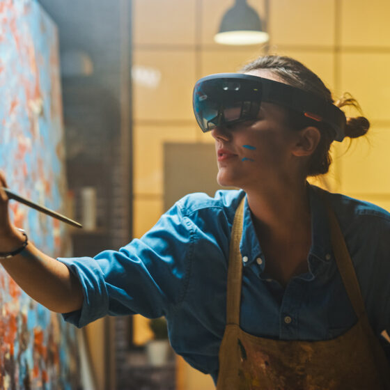 Talented Female Artist Wearing Augmented Reality Headset Working on Abstract Digital Painting, Uses Paint Brush To Create New Concept Art Using Virtual Reality Interface. High tech Creative Modern Studio
